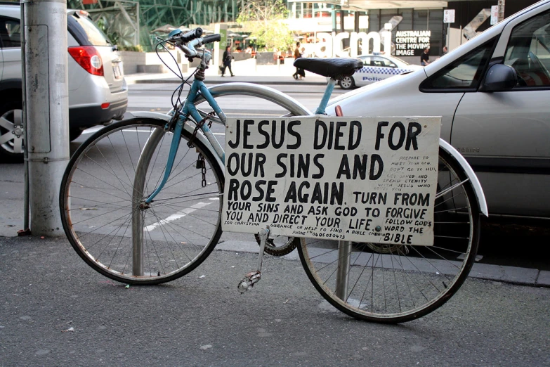 a bicycle is leaning up against a pole with a sign on it