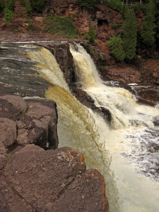 two large rocks are by a waterfall as it pours