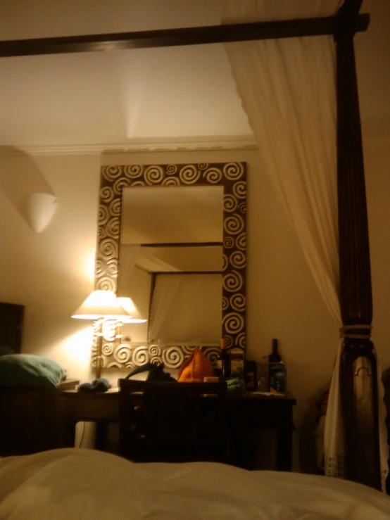 a bedroom with a four post mirror, dresser and lamps