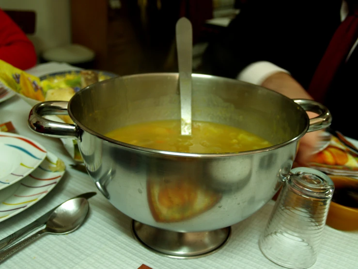a pot of soup and spoons on the table