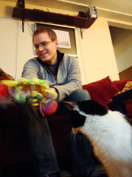 a man sitting on a couch next to a cat