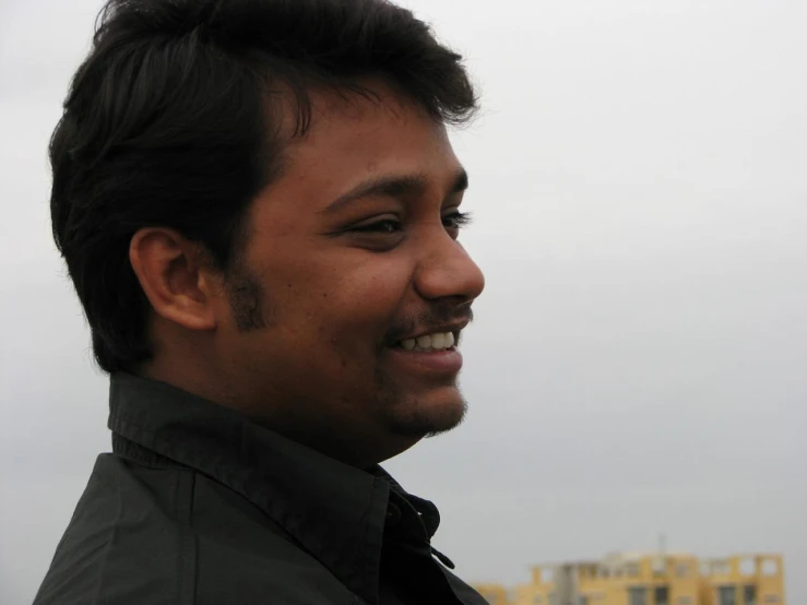 a man in black jacket smiling with his eyes open