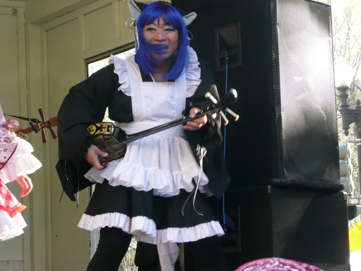 a woman in a cosplay, holding two swords and standing in front of a stage