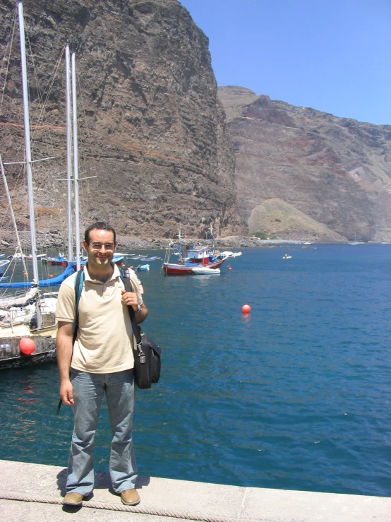 a man with a backpack stands at the edge of a river