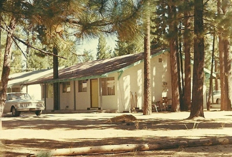 a white car parked in front of a house surrounded by trees