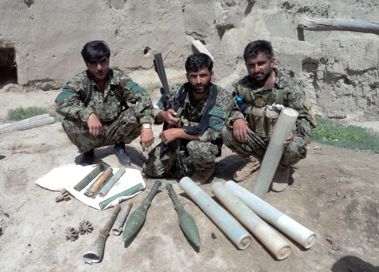 a group of three men pose with weapons