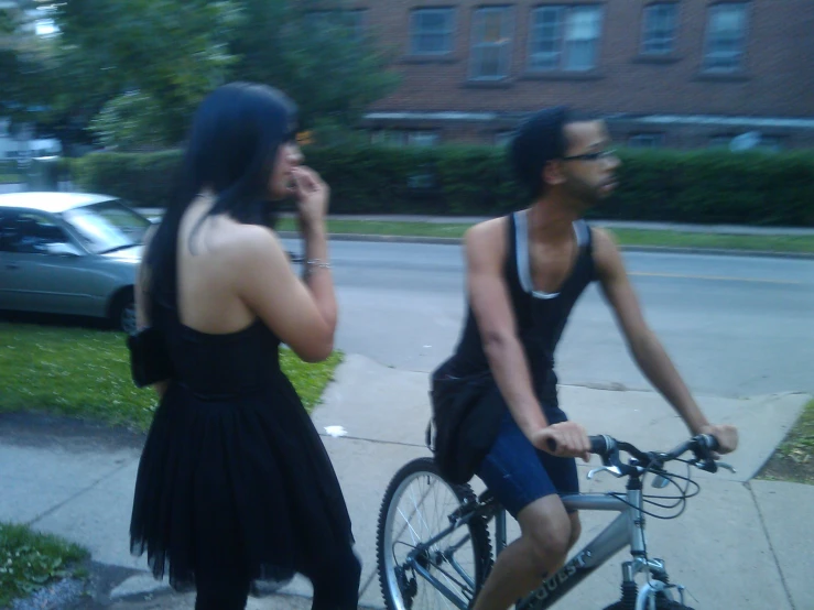 two young woman riding bikes talking on cell phones