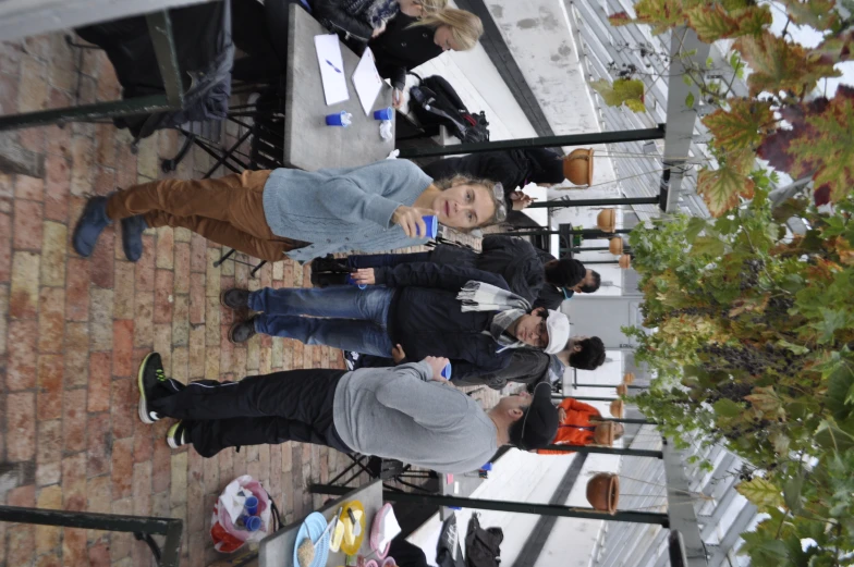 a bunch of people standing around tables on a brick sidewalk