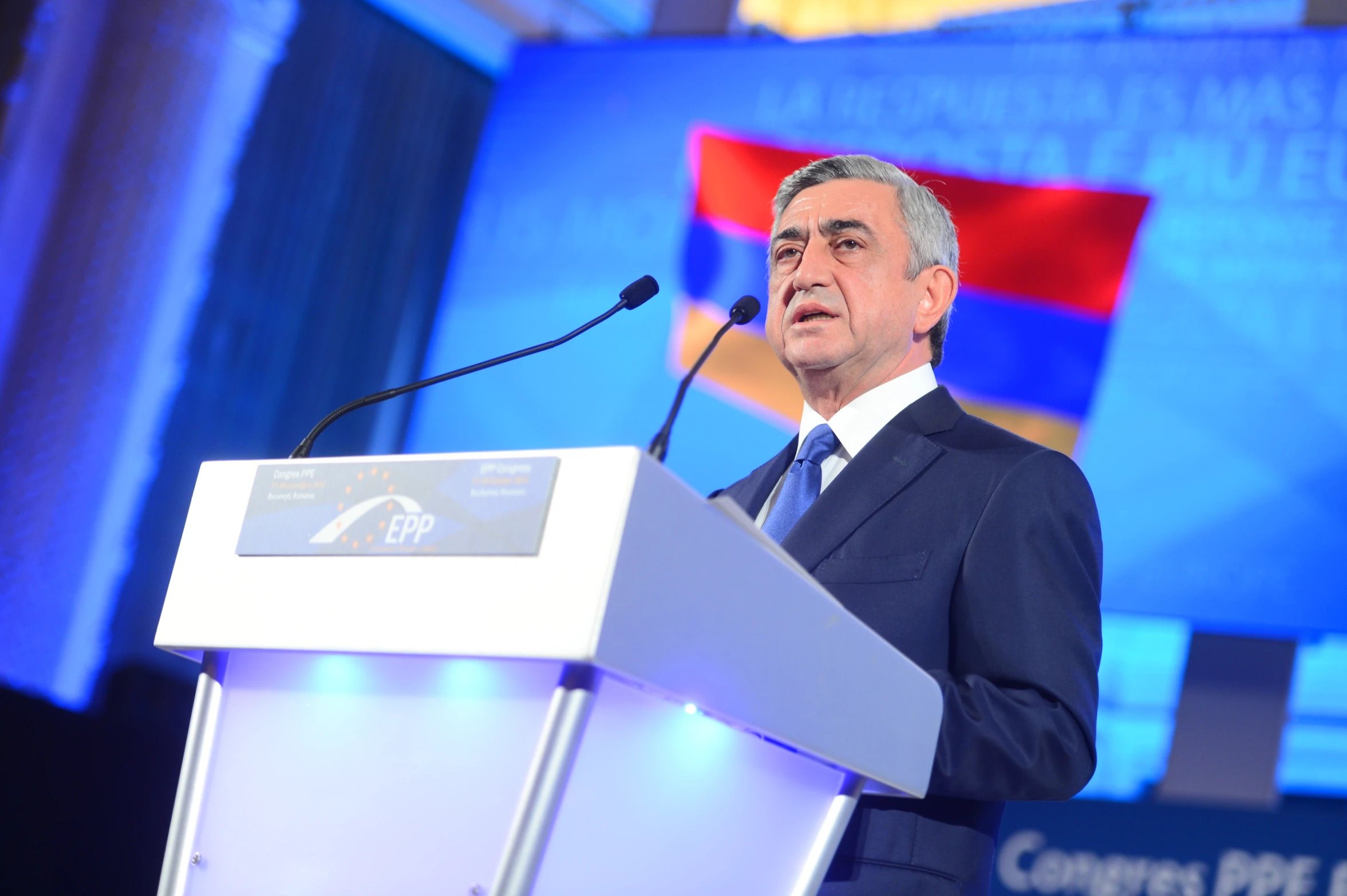 a man in a suit speaking on a podium