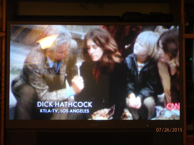 an older television screen shows two girls and a man talking on the phone