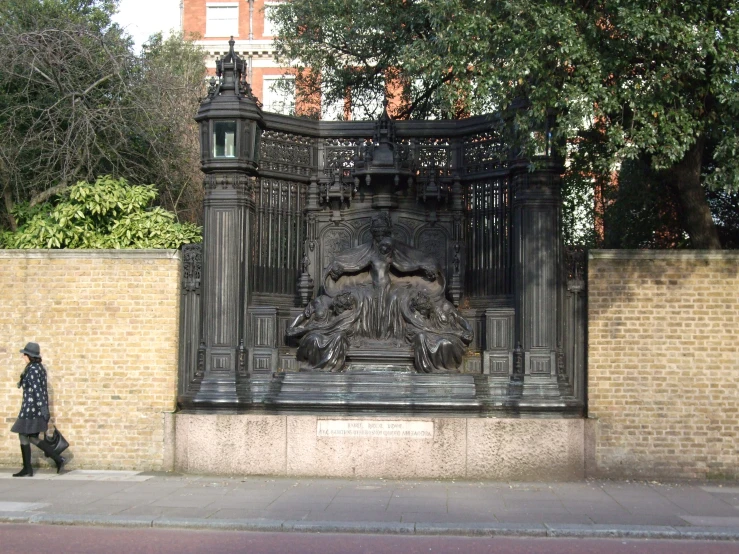 a black iron gate with a woman walking behind it