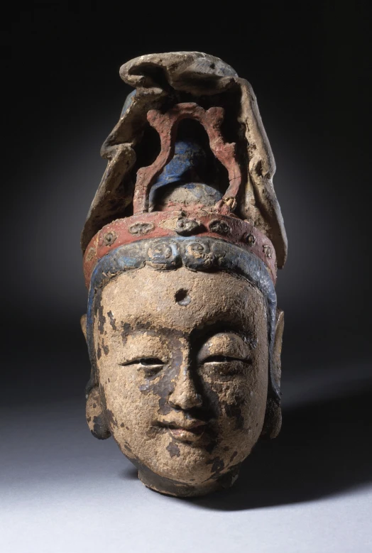 an ancient stone buddha head in profile with eyes closed