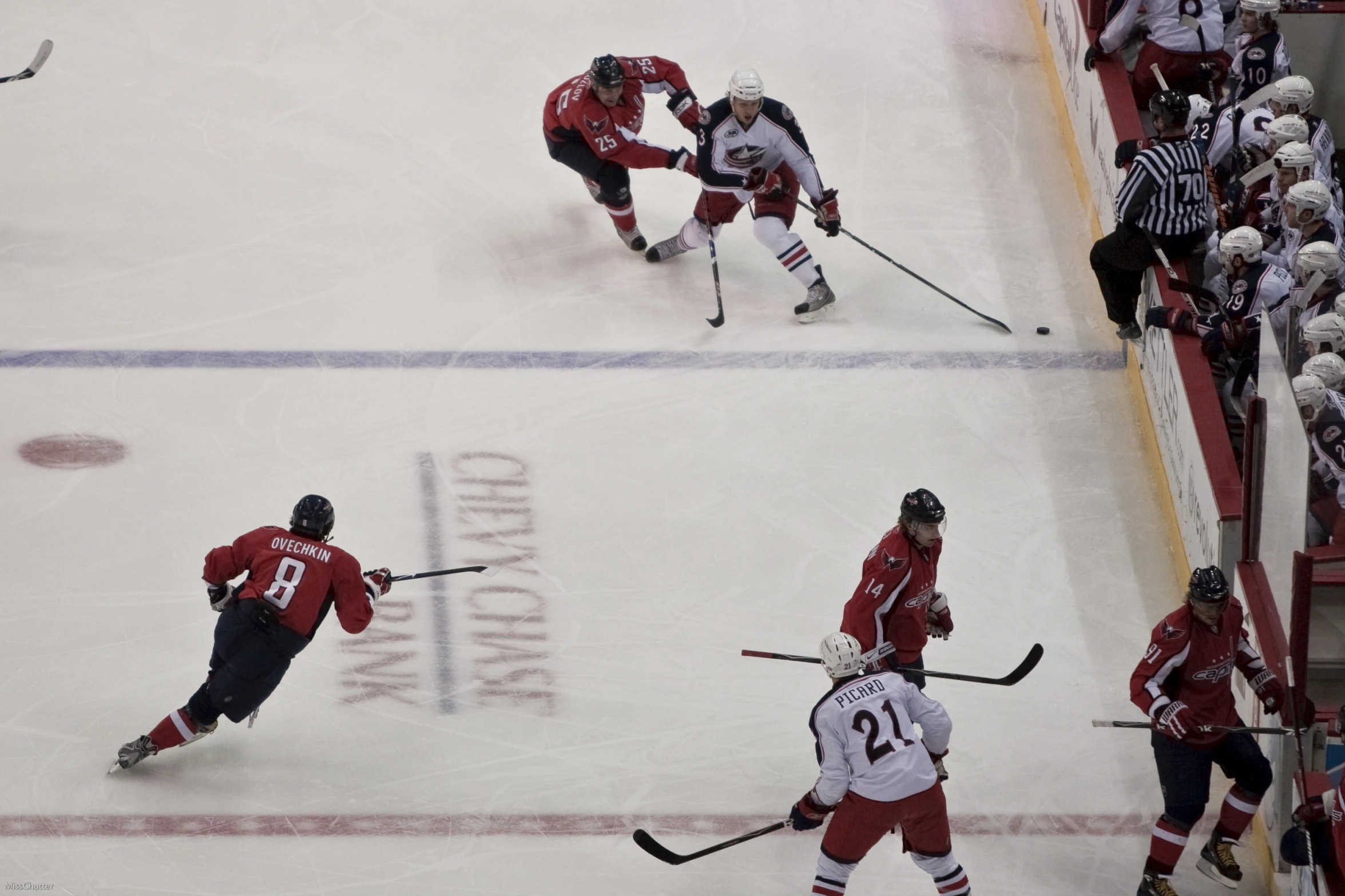 four men in red uniforms playing hockey on the ice