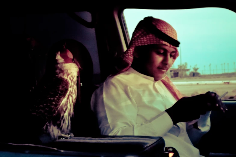 a woman wearing a red hijab holding an owl while in a car