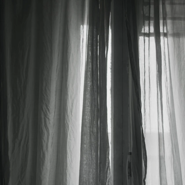 an empty table next to an open window with sheer curtains