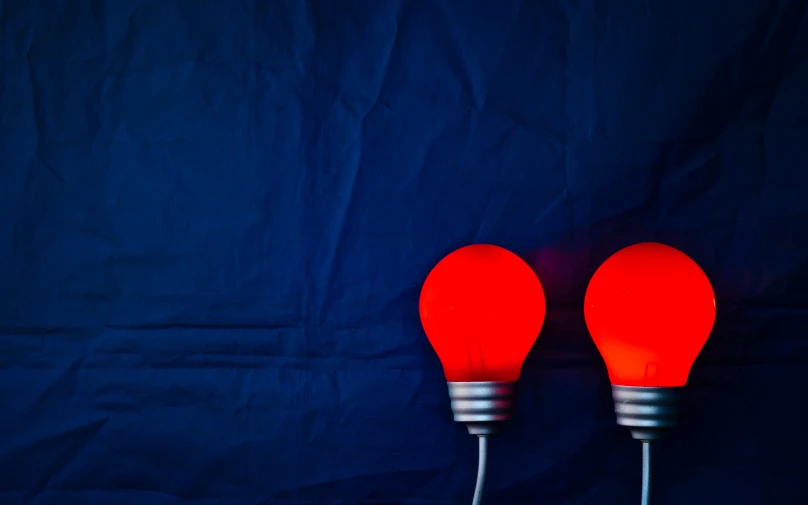 two red lamps sitting on a dark blue surface