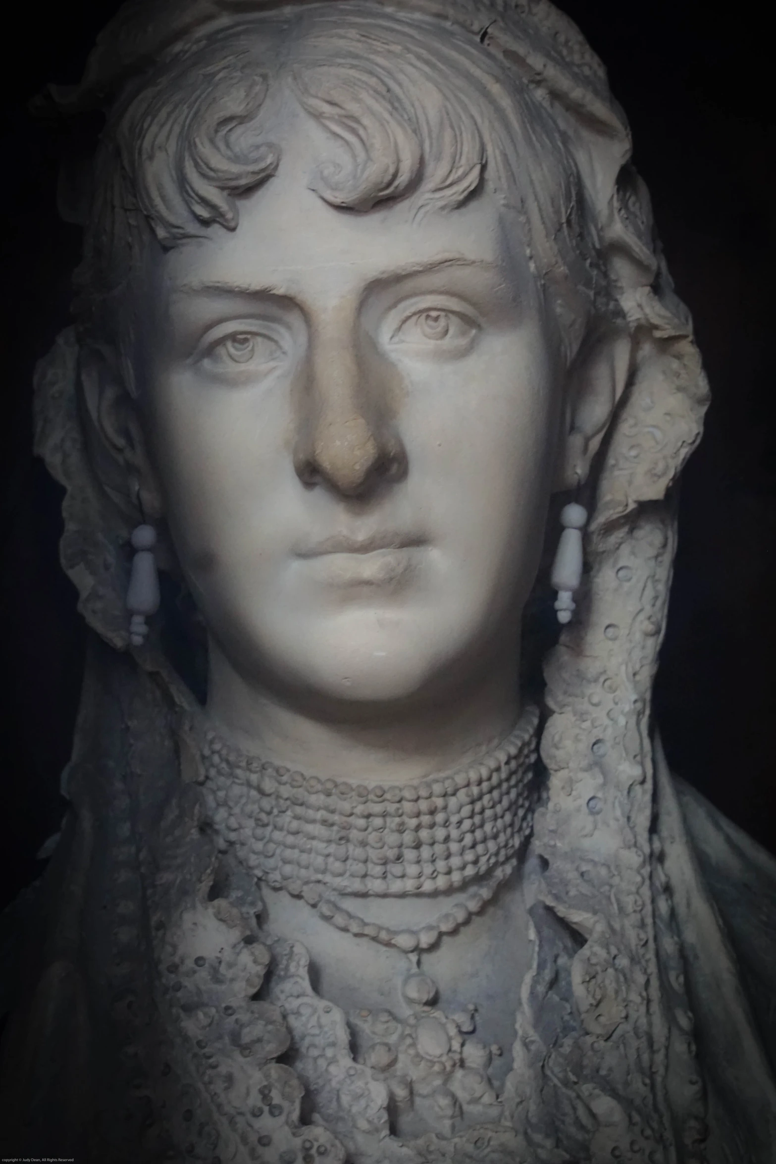 a white head statue on display next to a wall