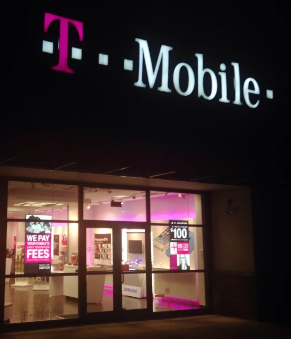 a t - mobile store lit up at night with people walking in front