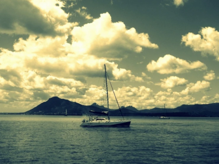 two boats floating on the ocean under cloudy skies