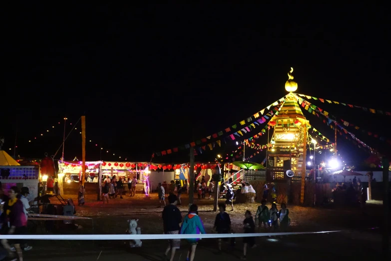 people walk around and in front of an illuminated carousel