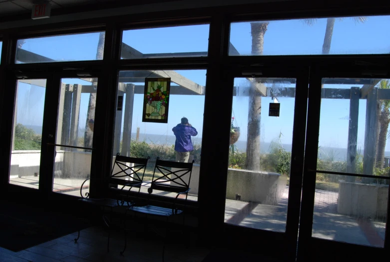 a person standing near glass doors looking out on the ocean