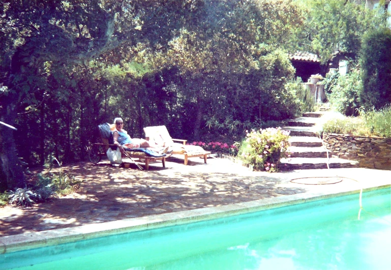 a man sitting in chair next to a pool