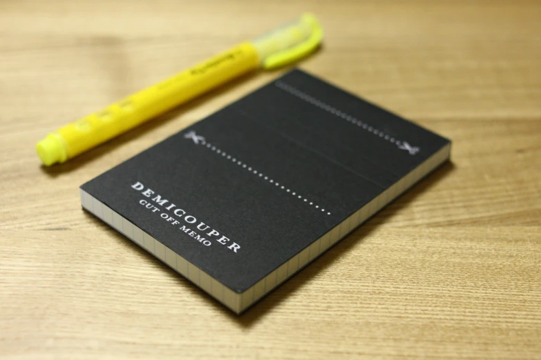 a book on a wooden table with a yellow pen