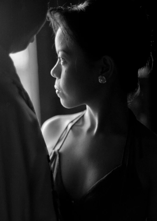 a black and white pograph of a woman looking out a window