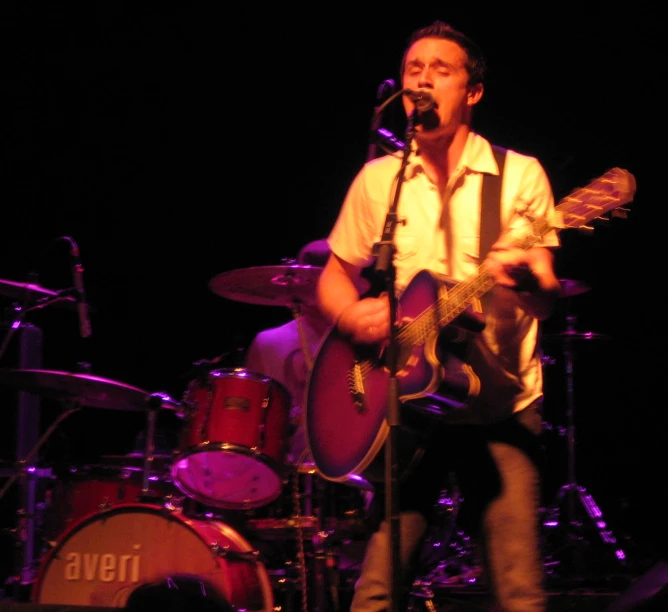 a man playing guitar while singing into a microphone