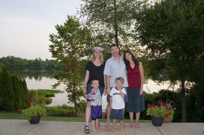 four people, a boy and a girl pose for a po by the lake