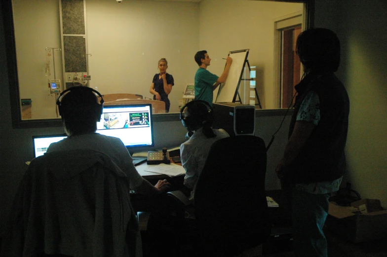 some people standing around a laptop on a desk