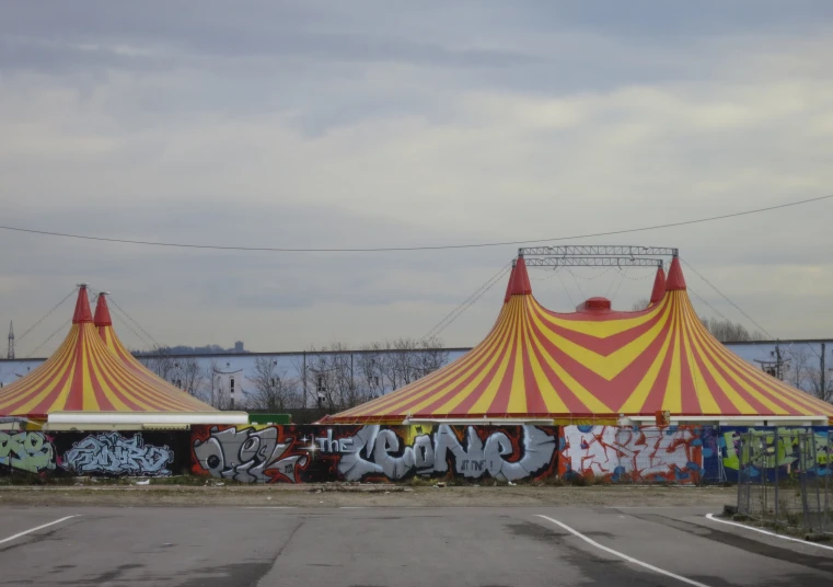 large circus tents covered in graffiti in a parking lot