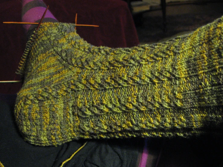 someone knits a green and yellow sweater from some yarn