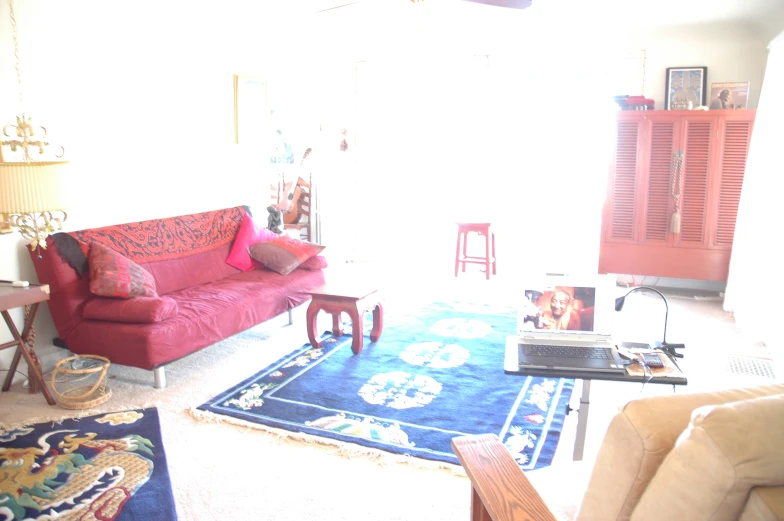 a living room with red couch and blue rug