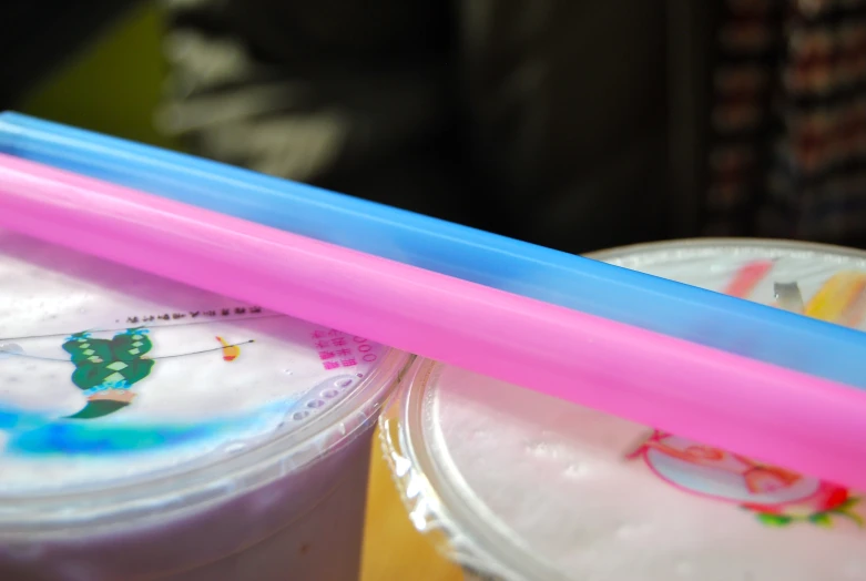 some straws with pink and blue tips next to a drink