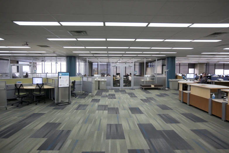 an empty office with checkered flooring, multiple desks and large windows