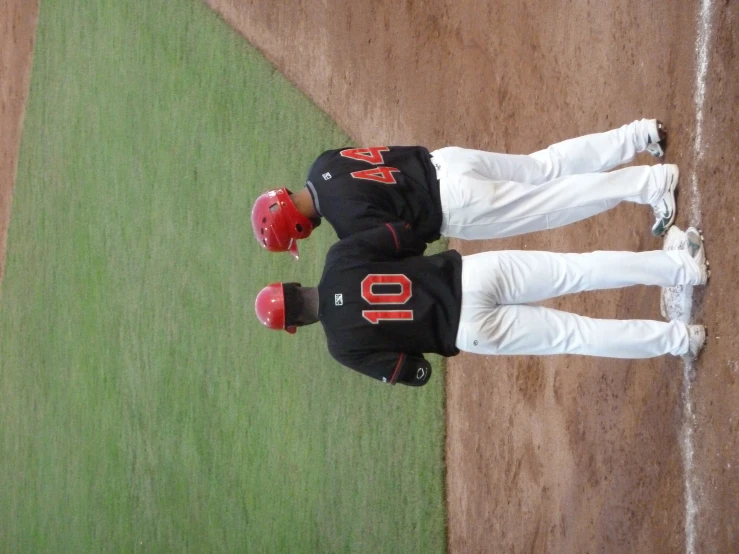 two baseball players in white and black standing at home plate