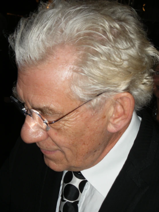 a close up of a person wearing glasses and a suit