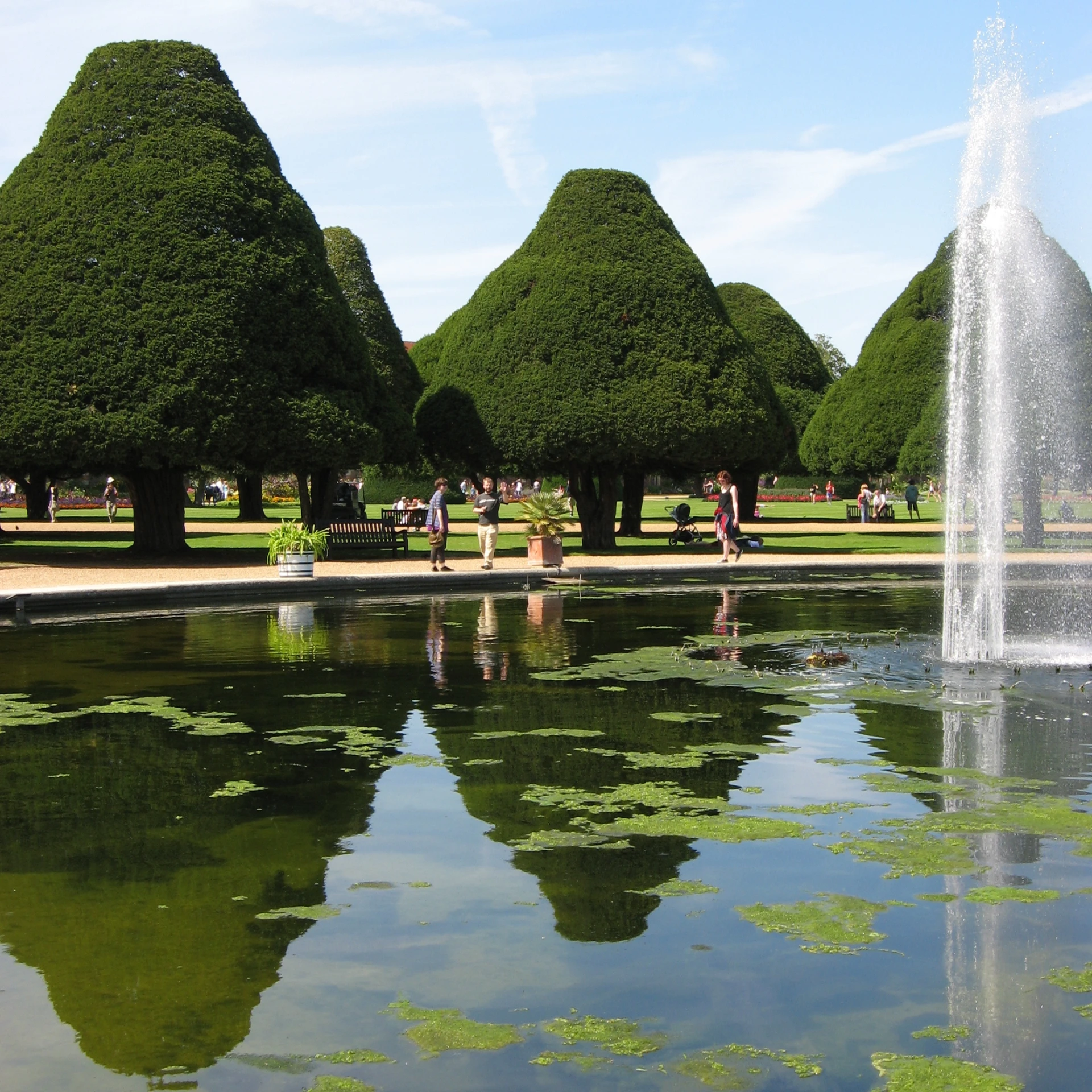 a pond in a park with a clock tower in the back