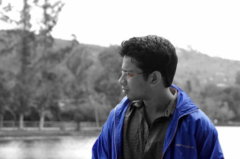 a young man wearing a blue jacket, sunglasses, and a black tie