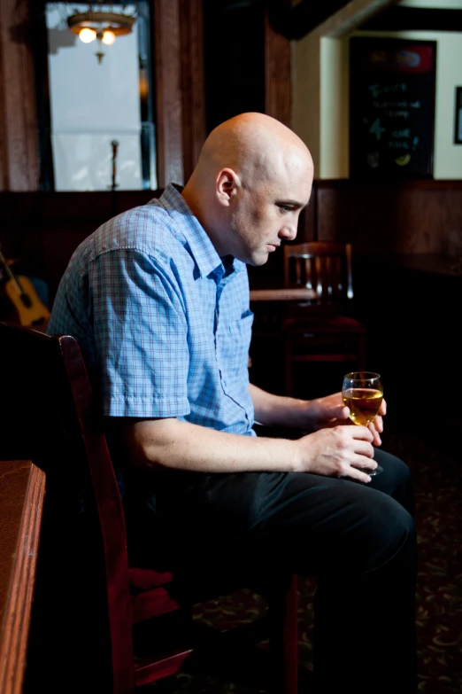 a man sitting in a chair holding a glass in his hand