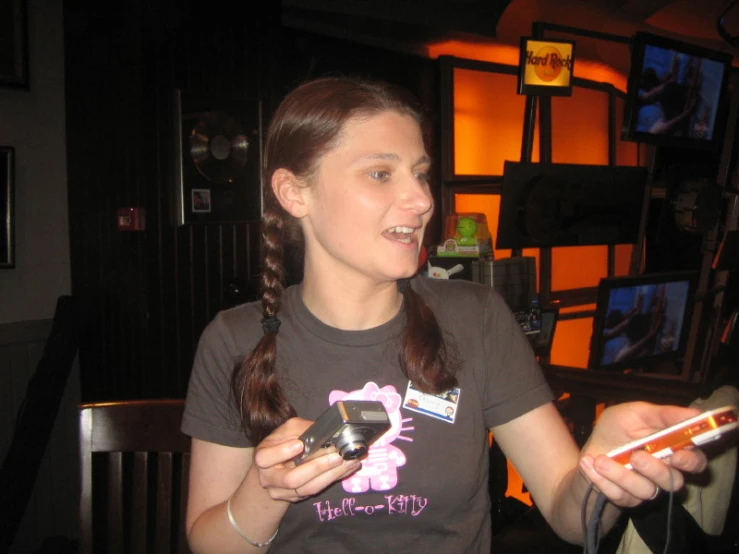 a woman holding her cellphone and standing next to a television