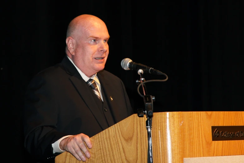 a balding man is giving a speech from behind a podium