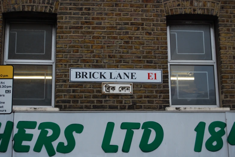 a sign is posted near two windows on a brick building