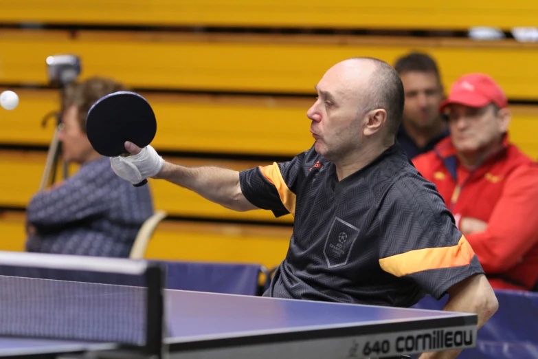 a ping pong player holds up his racket to throw the ball