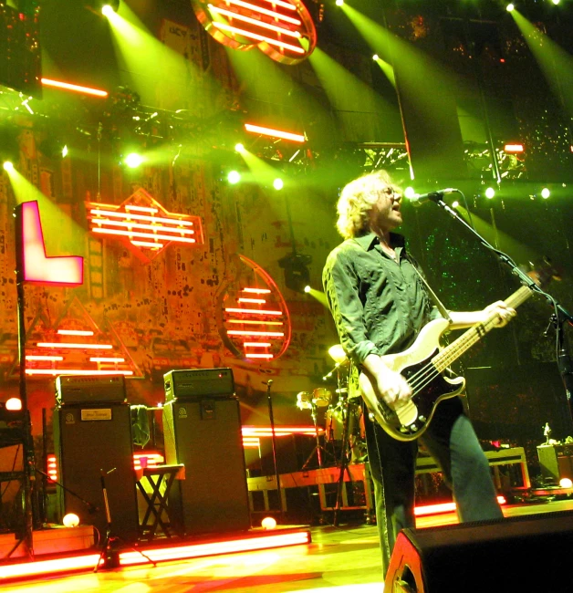 a man playing guitar on stage with some green and yellow lights