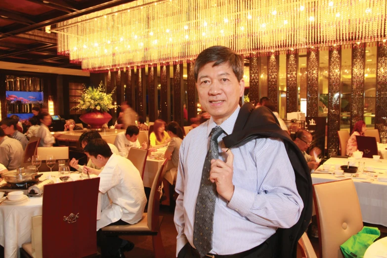 a man standing with his tie around his neck in a fancy restaurant