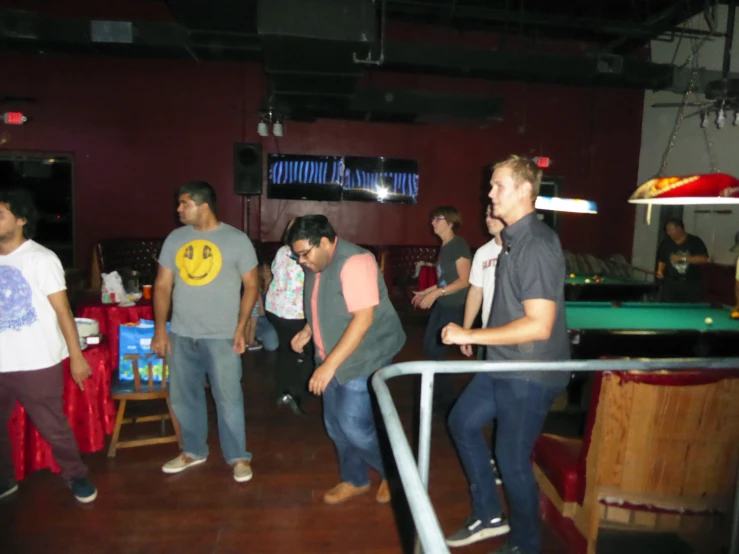 people are standing in a large room playing the game on the pool