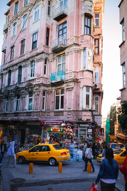 an older building has a lot of people in the streets and cars around it