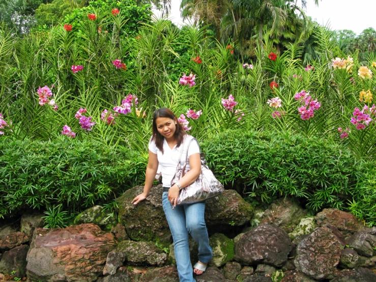 a woman is sitting on rocks next to flowers